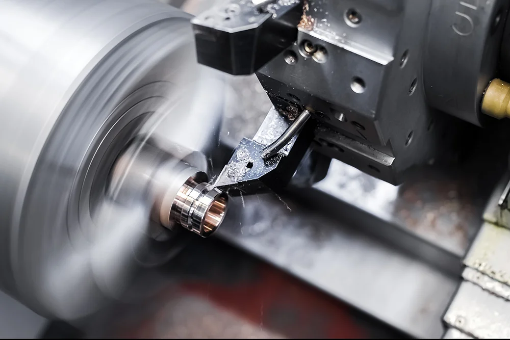 Nahaufnahme einer Drehmaschine im Betrieb, die ein Metallstück formt. Das Metall rotiert schnell, mit sichtbarer Bewegungsunschärfe. Das Schneidwerkzeug bearbeitet das Werkstück präzise, umgeben von Metallspänen und Oberflächendetails.